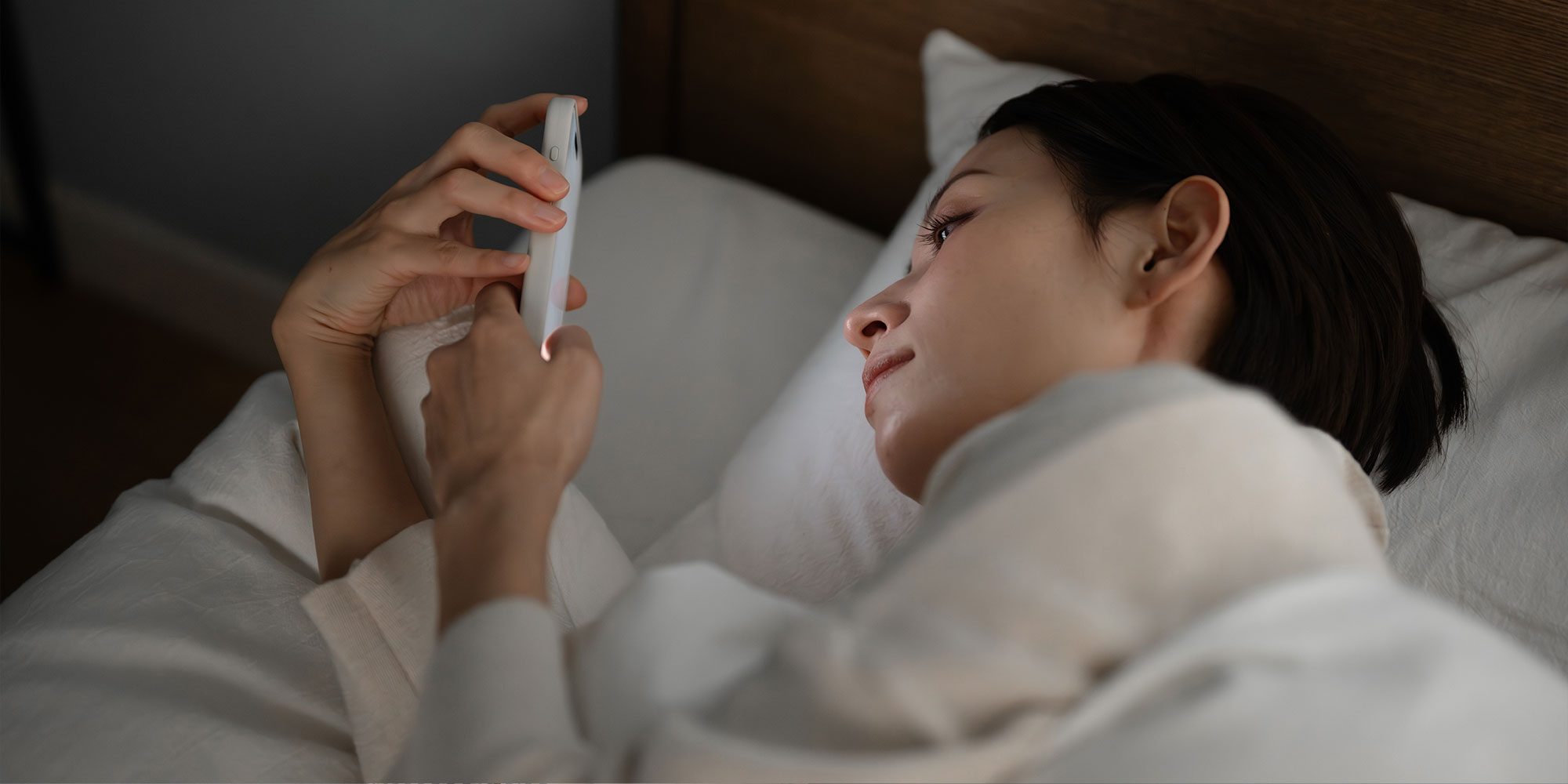 寝る前にスマホを見る女性