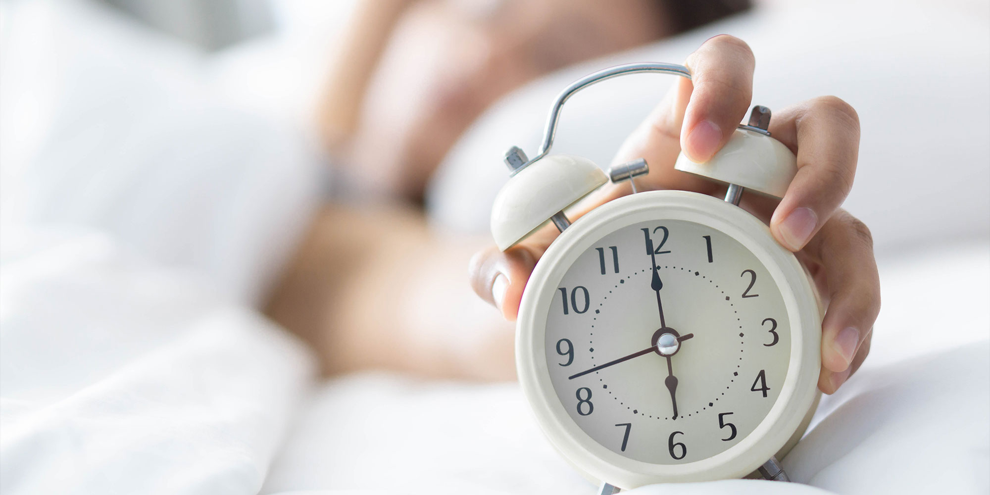 目覚まし時計を止める女性