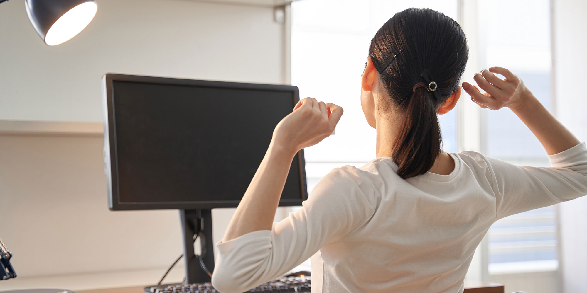 仕事の合間に伸びをする女性