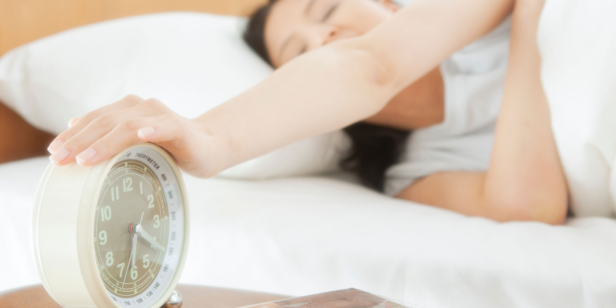 目覚まし時計を止める女性