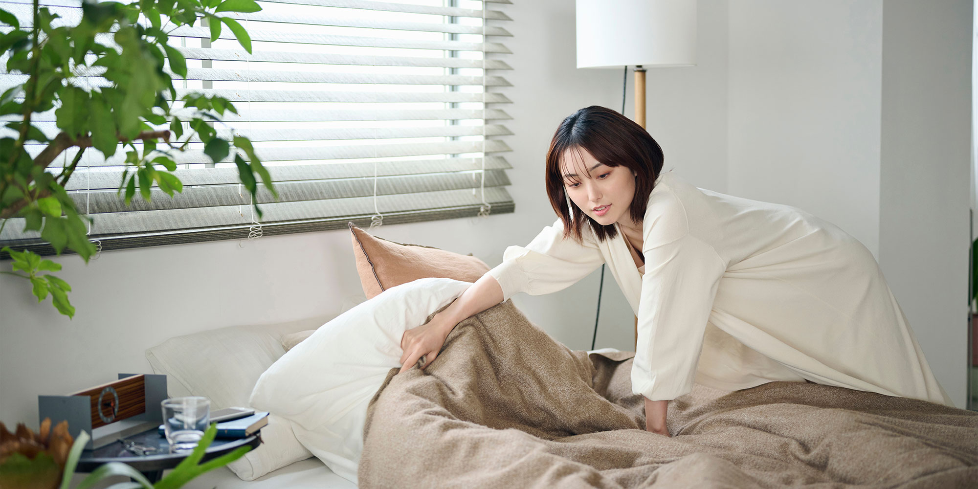 ベッドメイクをする女性