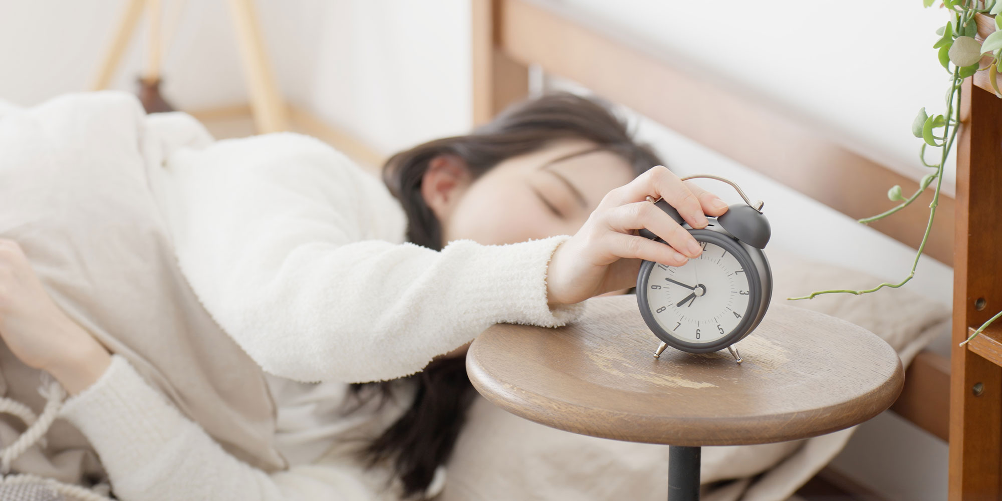 目覚まし時計を止める女性