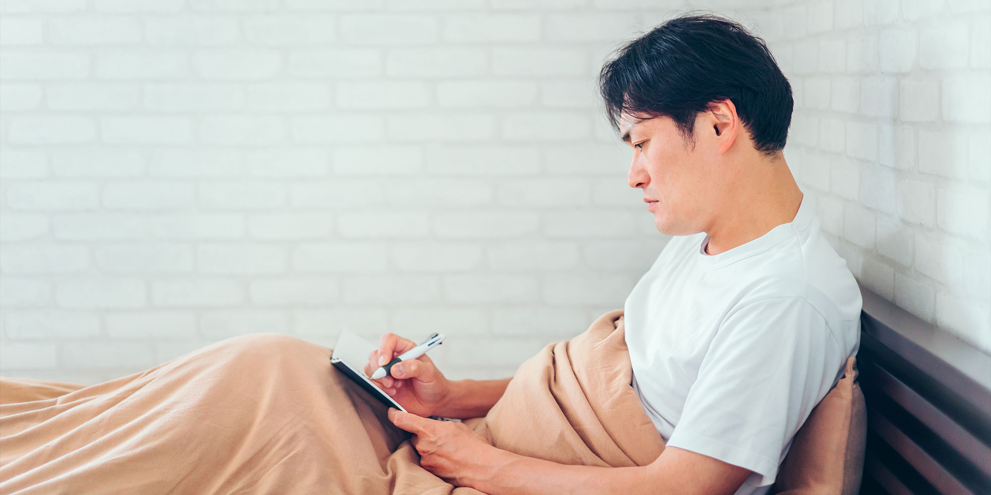 ベッドでメモをとる男性
