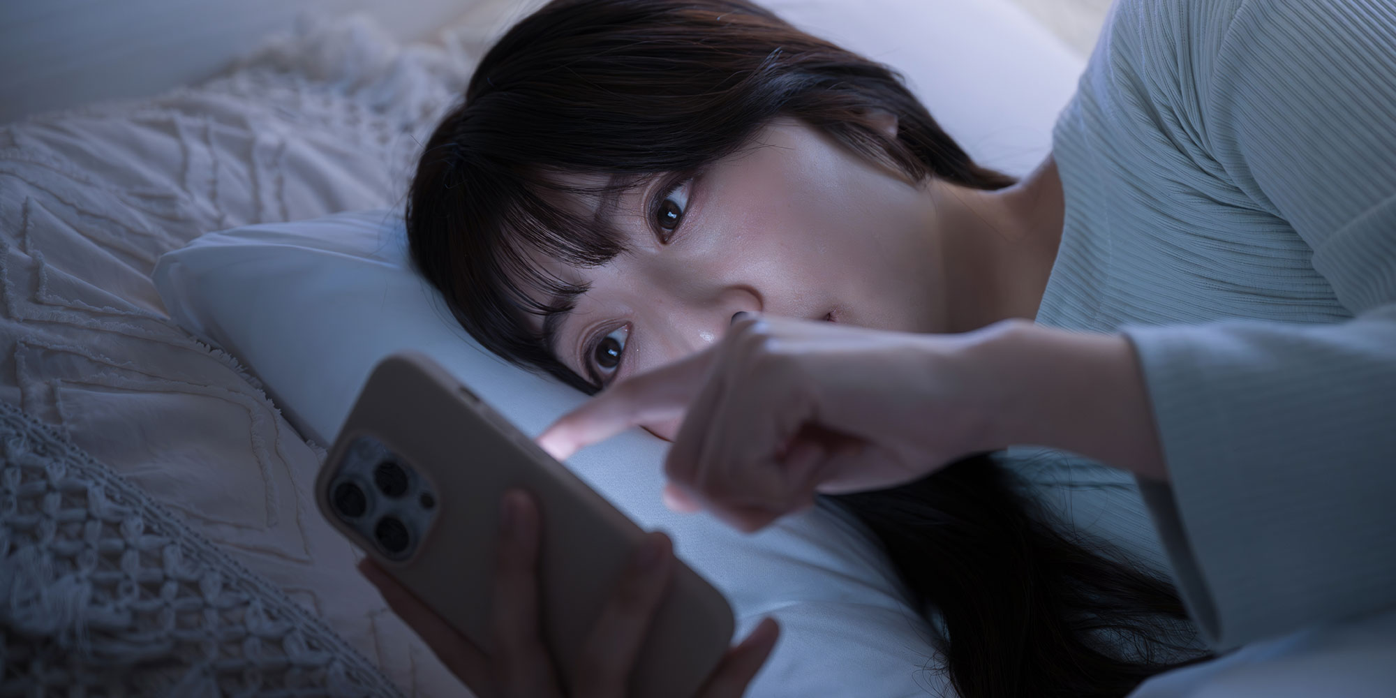 寝ながらスマホを触る女性